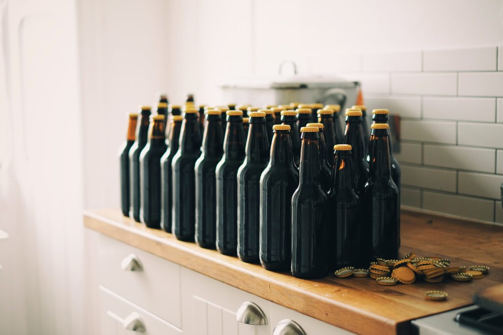 Black beer bottles with yellow caps on a shelf.