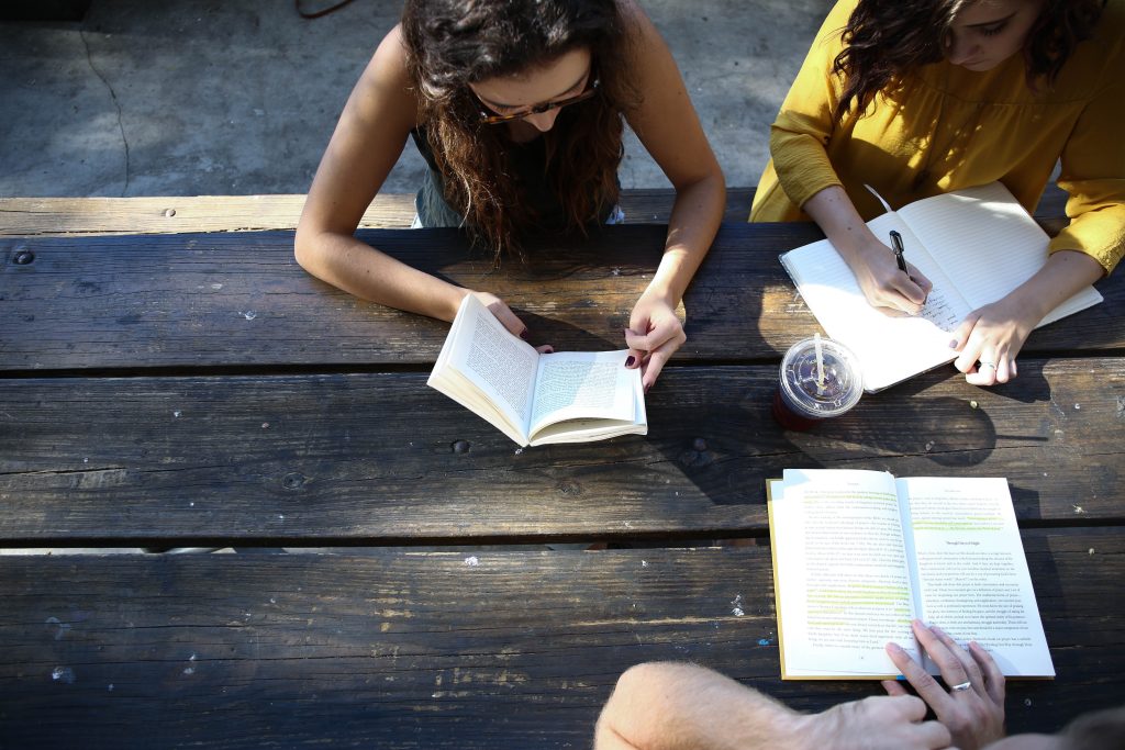 Three girls reading a book. This article is about mental health.