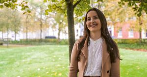 A young white female climate crisis activist smiling while standing in a park