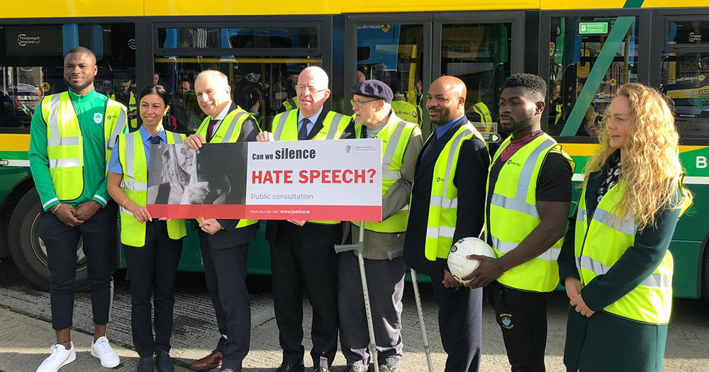 Minister for Justice and Equality, bus drivers, and sports players standing in front of a bus as part of hate speech consultation launch.