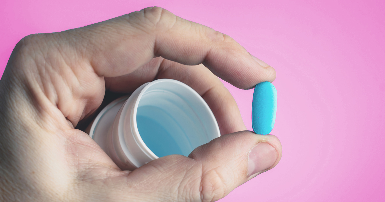 PrEP in Ireland: A hand holding a blue pill and a pill bottle.