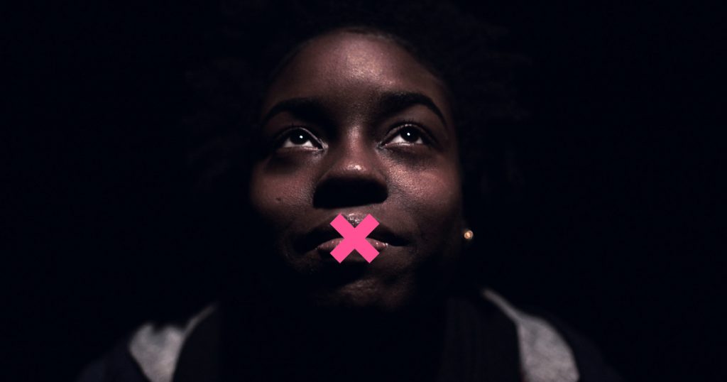 Coming out in a homophobic family - Close-up of a young POC with a pink X on their mouth
