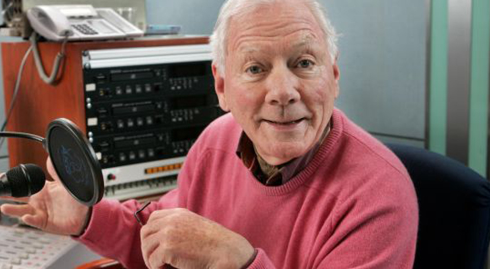 Gay Byrne smiling in a radio recording studio.