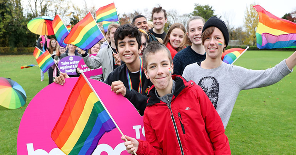 School children wearing rainbow face paint and holding rainbow flags in support of BeLonG To’s Stand Up Awareness week