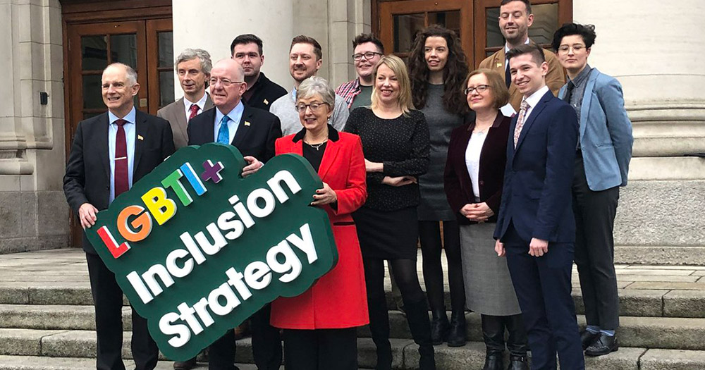 Minister Stanton and Minister Flanagan and other representatives holding a LGBT+ Inclusion Strategy sign