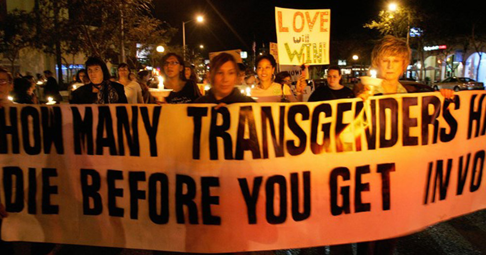 People holding a sign saying How many transgenders have to die before you get involved.