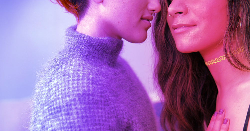 Close-up of two women about to kiss with bisexual colours