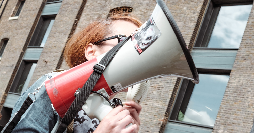 A woman holding a megaphone, it obscures her face
