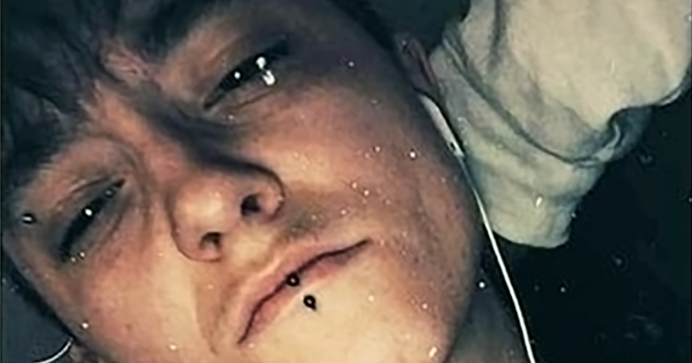Lesbian woman Charlie Graham lying in bed with headphones, she has recently been left covered in blood after a homophobic attack