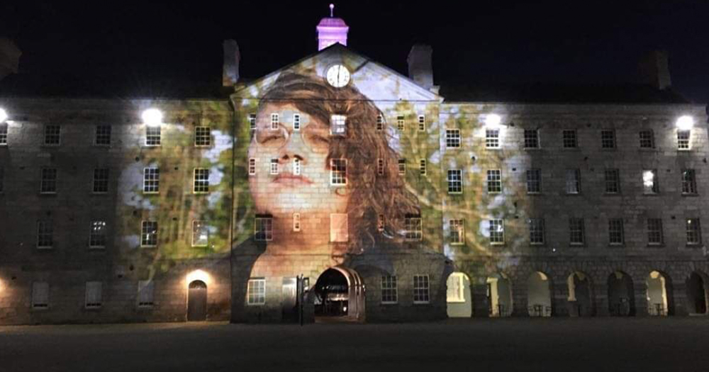 A portrait of a woman projected onto the side of a huge building at night