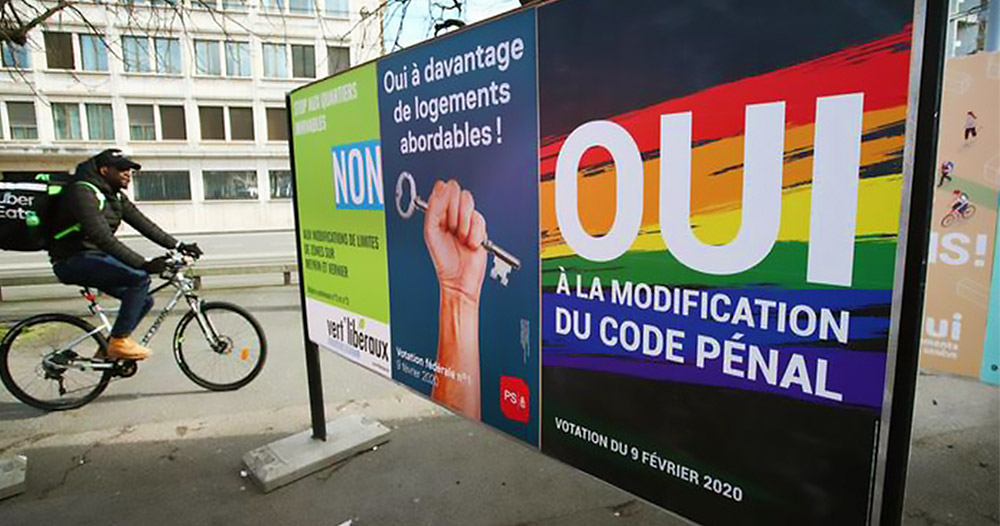 Man cycles past referendum posters. Switzerland discrimination