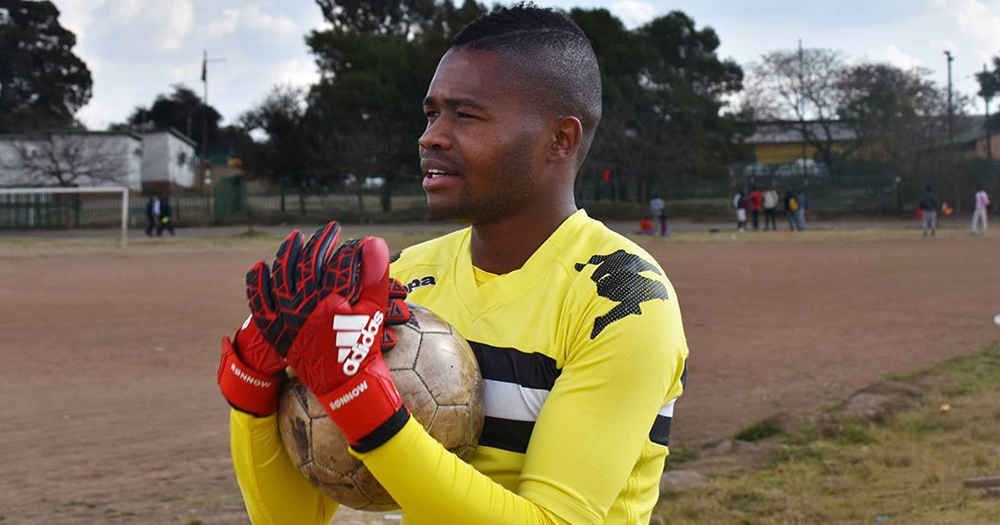 South Africa's first openly gay soccer player Phuti Lekoloane wearing a yellow jersey and holding a ball.