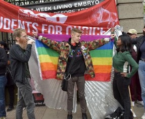 A group of three people with flags standing at a protest
