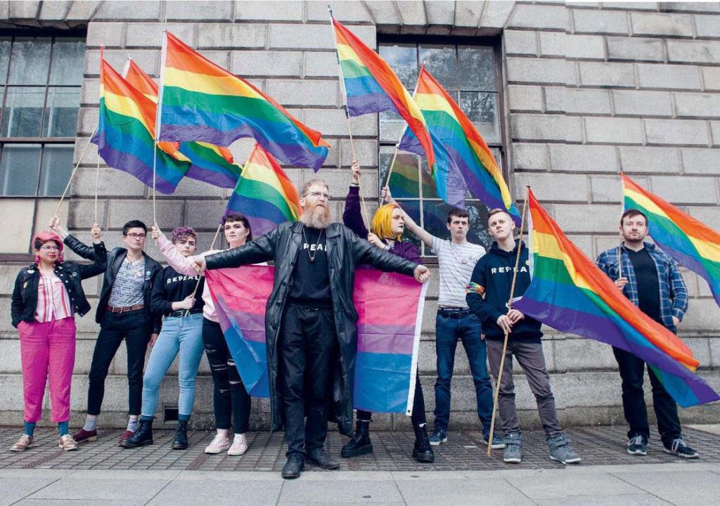 Jon Hanna with protesters holding a bisexual flag