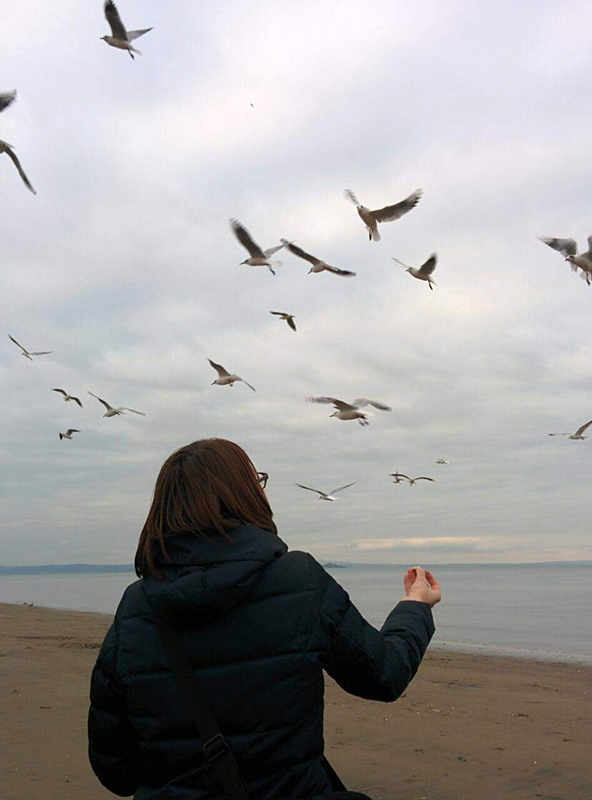 Russian woman at the beach looking at the sky and birds