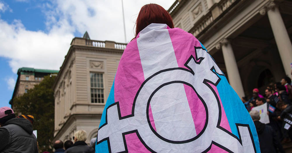 A person wearing trans pride flag in front of a building, a Guardian employee has recently shared her reaction to a published article
