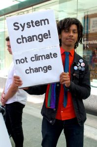 A young man in a jacket and tie holding a sign against climate change