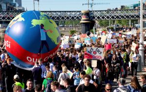 A crowd of marching young people holding signs and inflatable