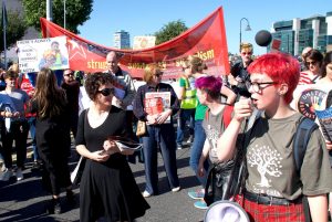 A crowd of marching young people holding signs and inflatables
