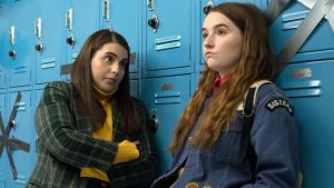 Two teenage girls lean against a row of lockers