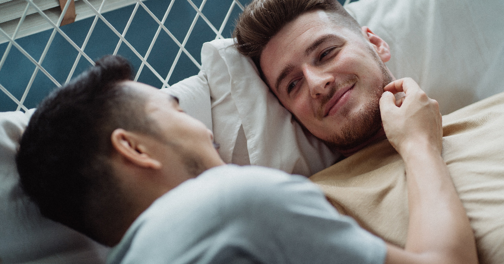 Two men lying in bed together