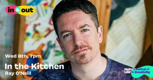 A smiling bearded man in a restaurant gazes at the camera.