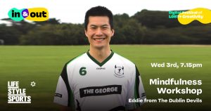 A smiling man in a football jersey stands in a field