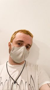A man with bleached hair wears a face mask
