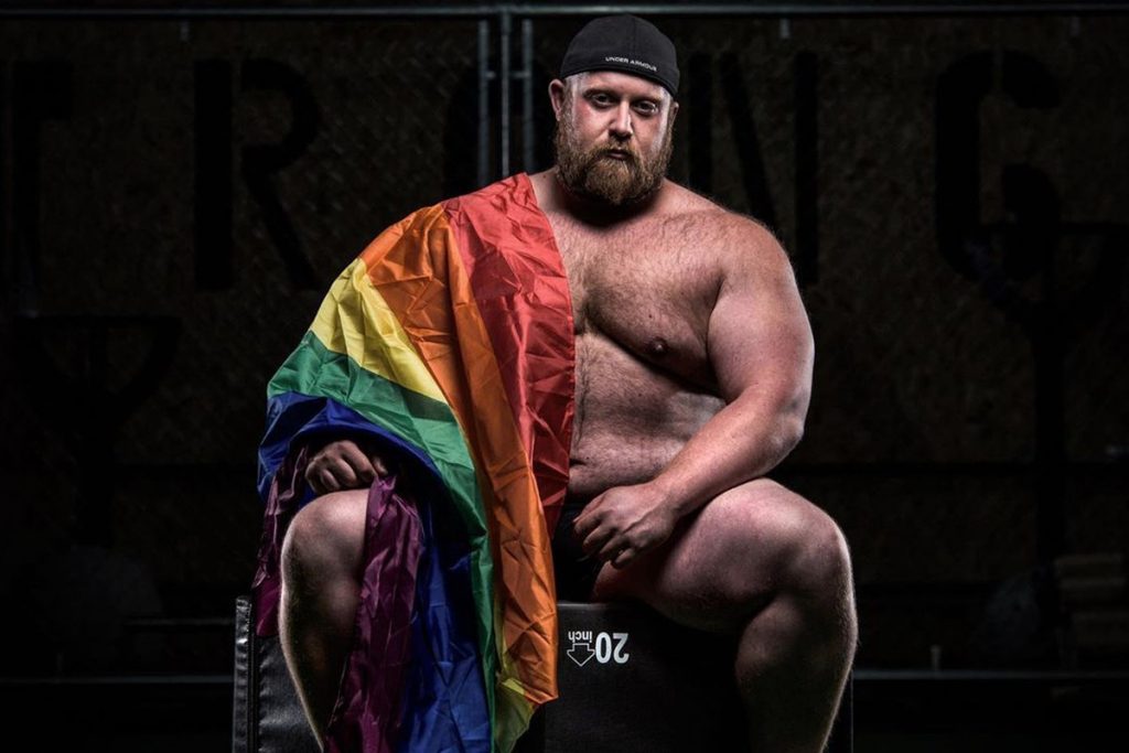 strongman draped in a rainbow flag 