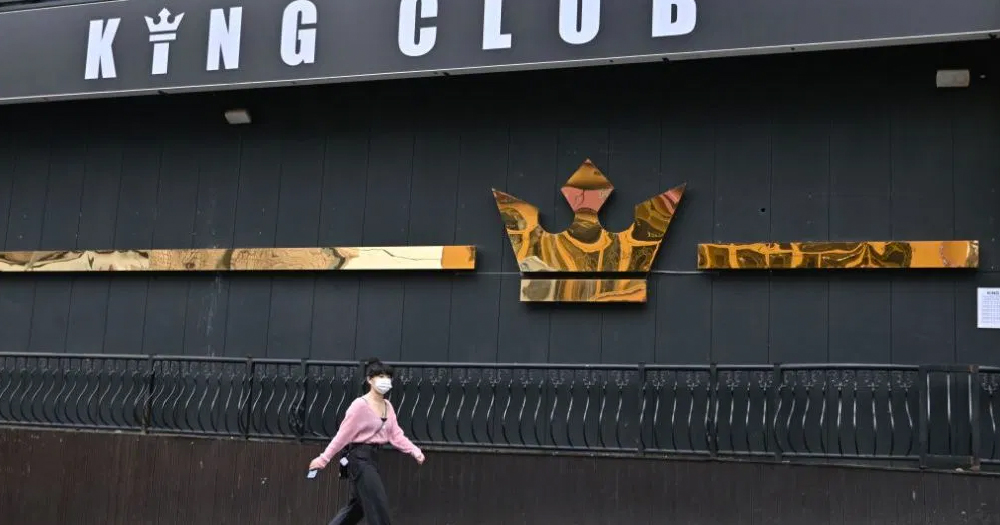 A woman wearing a facemask walks past a shuttered Korean club