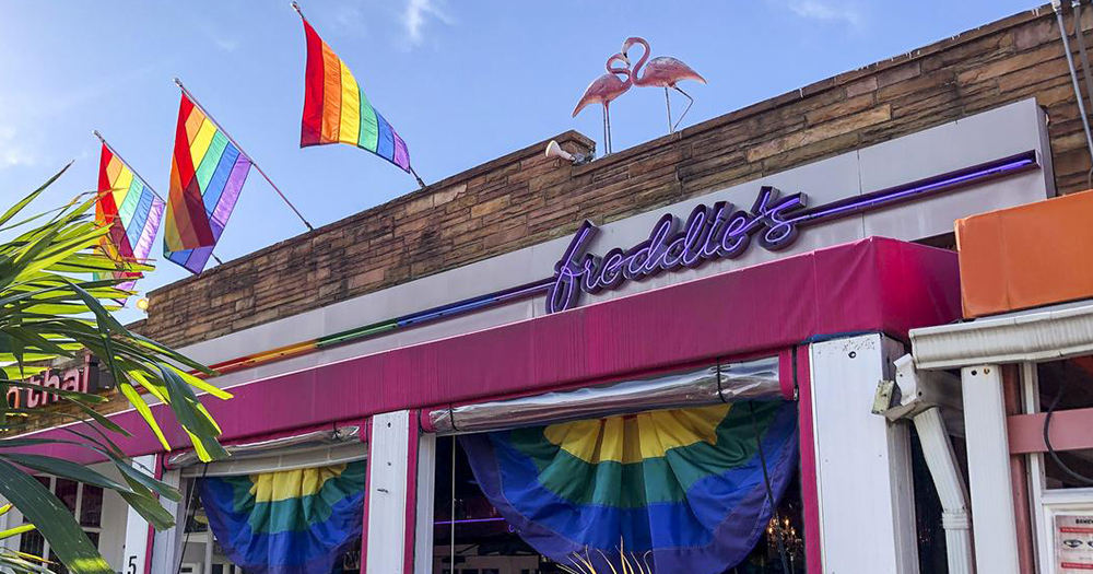 The exterior of a gay bar with flamingos and rainbow flags