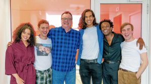 One woman and five men smilingly pose for a photo