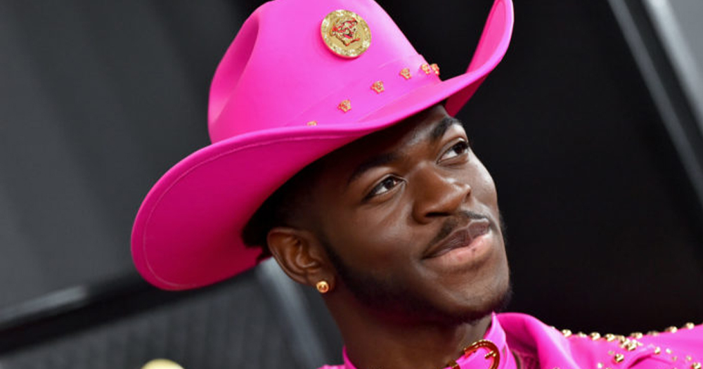 Lil Nas X - a young man wearing a pink cowboy outfit, poses at an awards ceremony