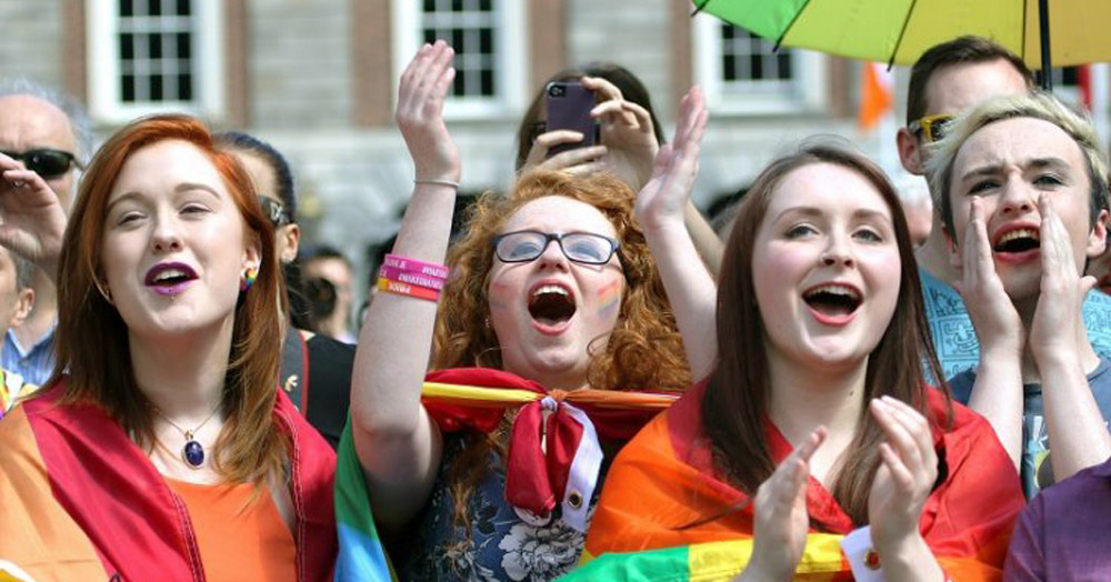 Young people cheering wearing rainbow flag during the marriage equality referendum announcement