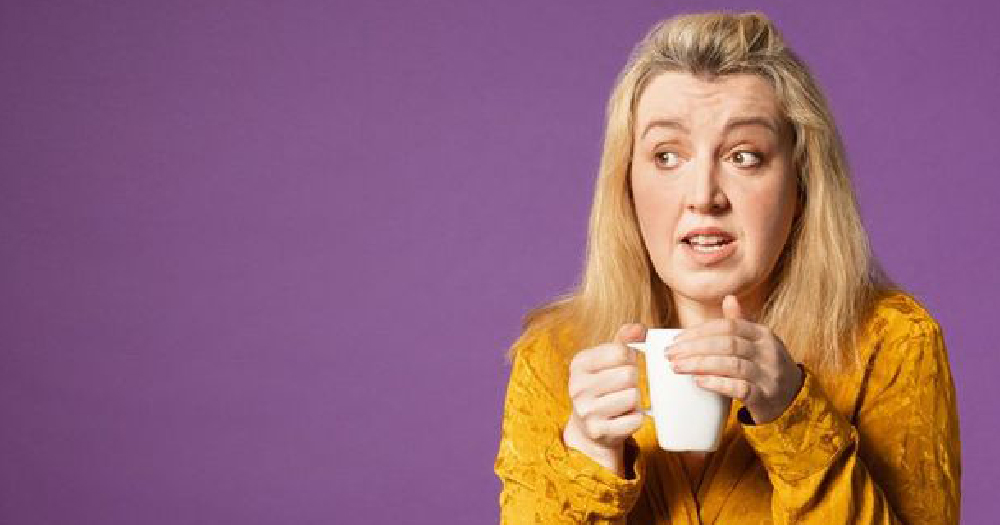 A blonde surprised looking woman holds a mug