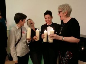 A group of four women holding candles and laughing