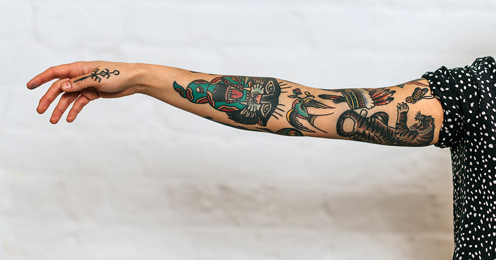 A tattooed female arm reaches out