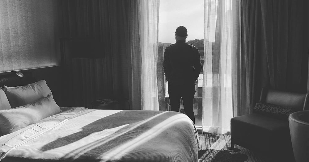 A silhouette of a man standing in the window of a hotel room