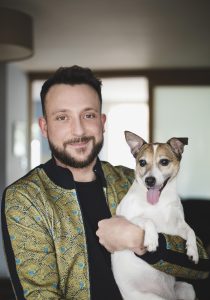 A smiling man in a house holding a dog