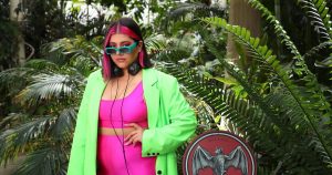 A young woman standing outdoors wearing sun glasses and a neon outfit