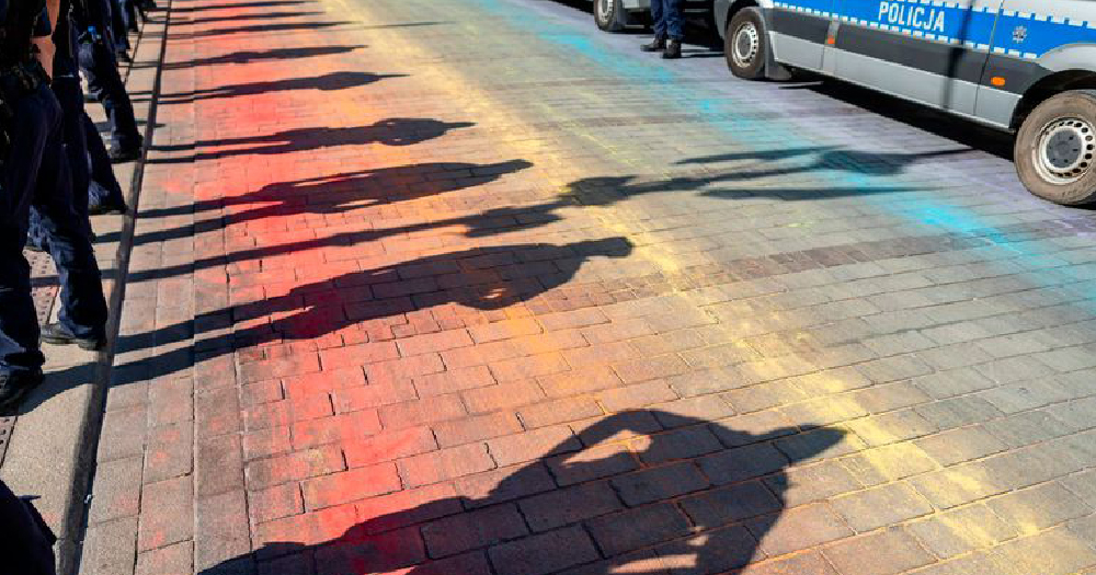 minister poland the shadow of police officers covers what is left of a road covered in chalk paint creating a rainbow flag