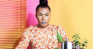 A person in a dress sits in a multicoloured room