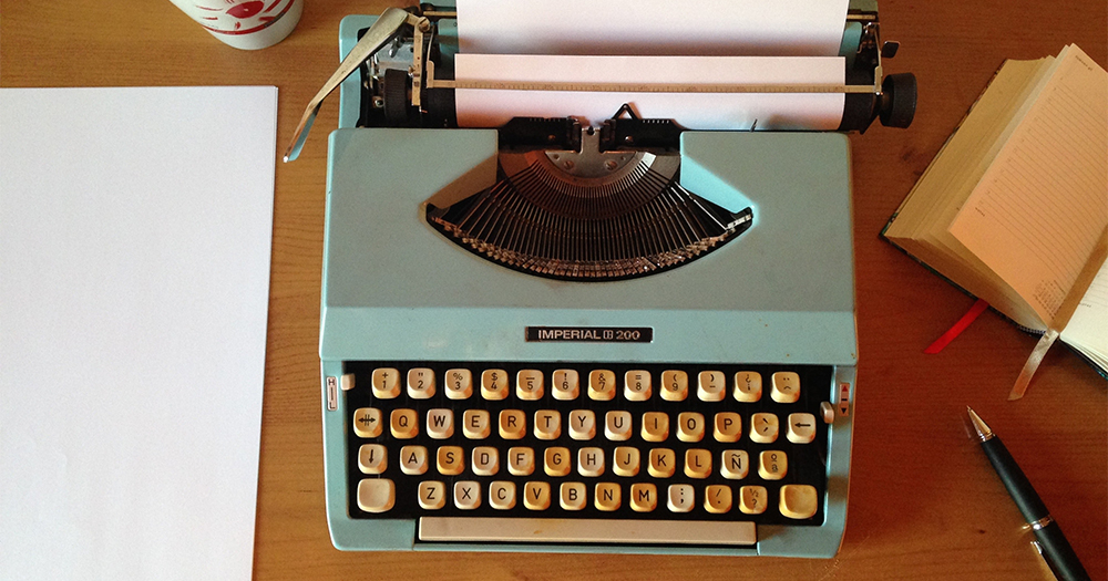 A typewriter, a pen and a book on a desk