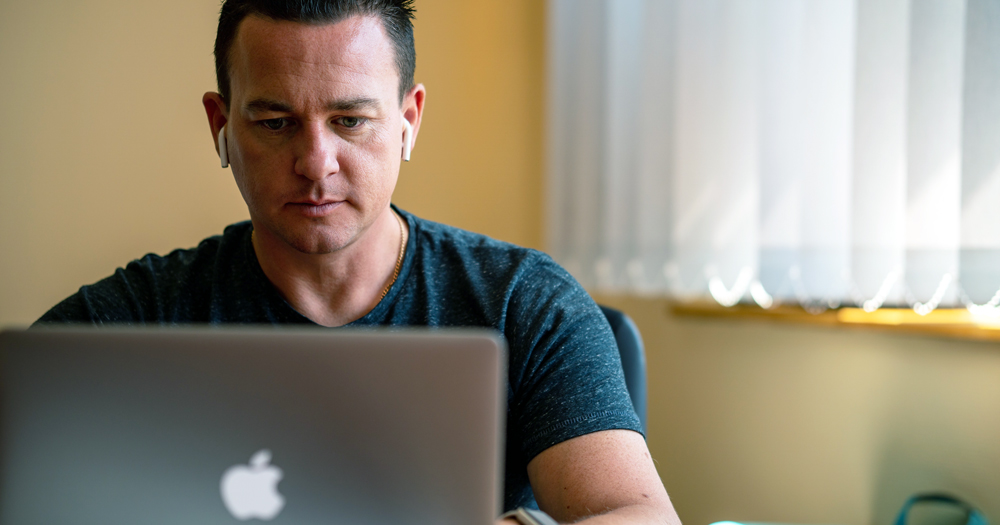 Man looking at his laptop. Amach LGBT Galway is organising free mental health workshops