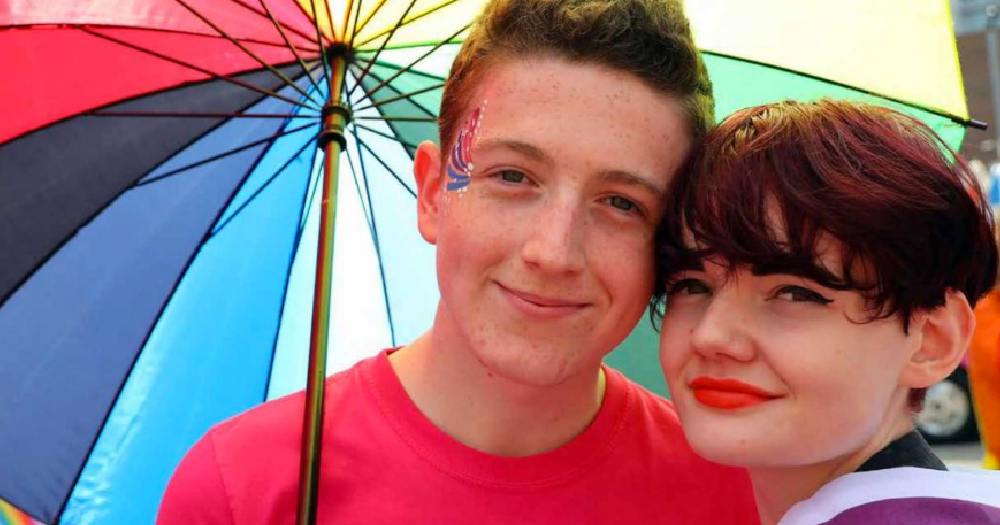 BeLonG To Annual Report 2019 two young people smile to the camera holding a rainbow umbrella