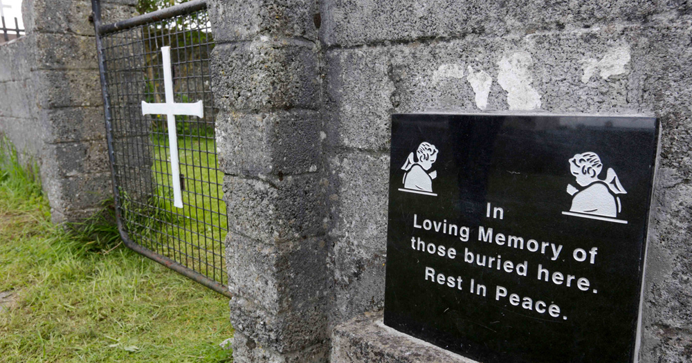 A picture of the mother and baby home memorial site at Tuam, concrete wall and wire gate