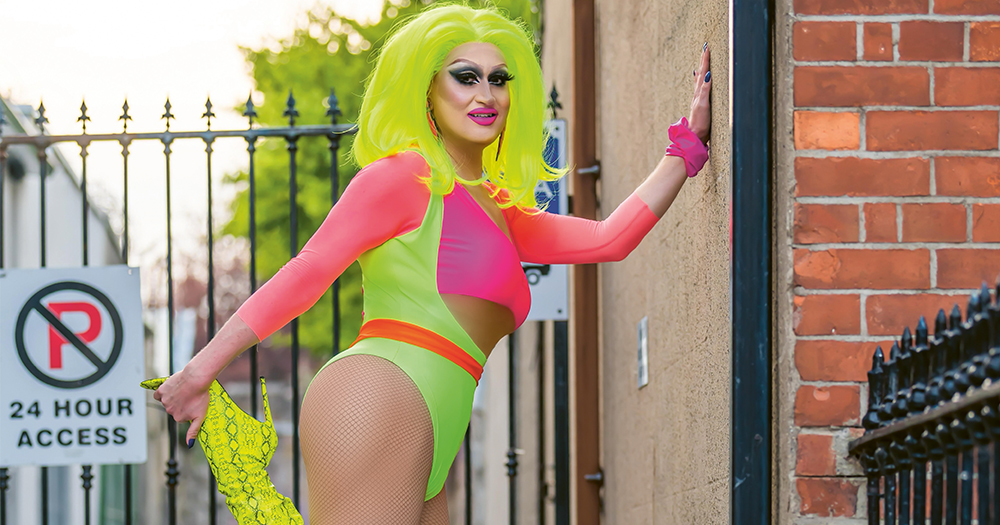 A drag queen in sports wear poses on a street