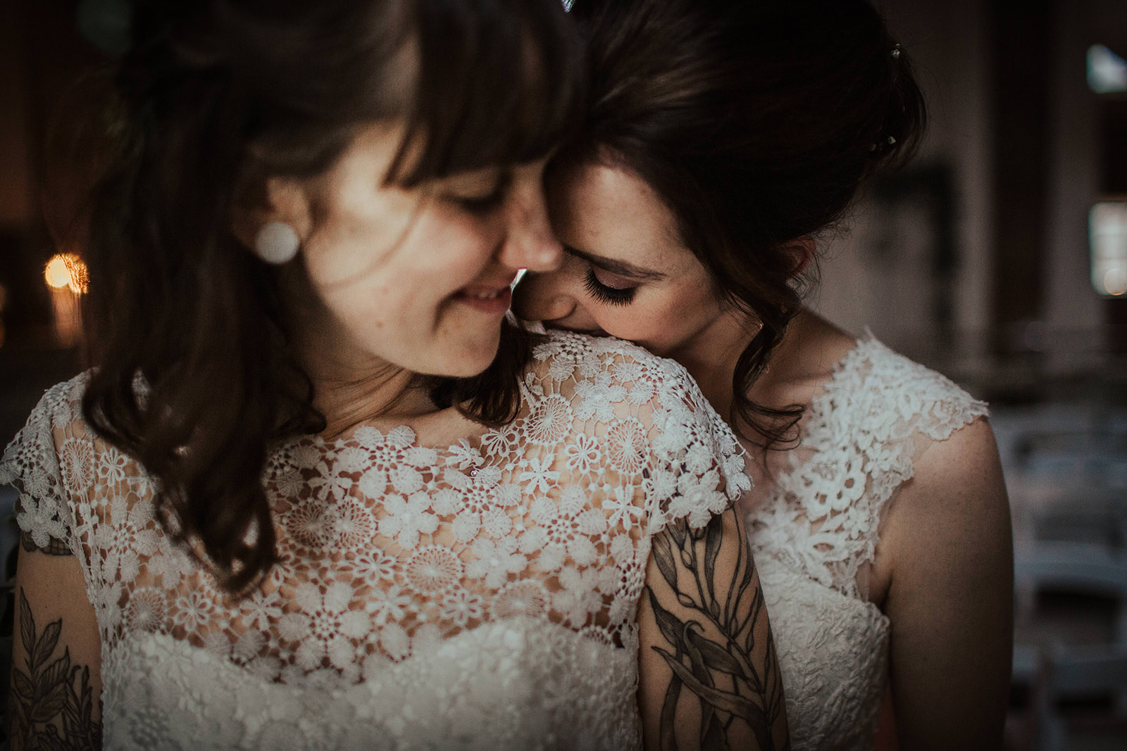 Sophie and Claire close together in their wedding dresses for their vows at the MillHouse