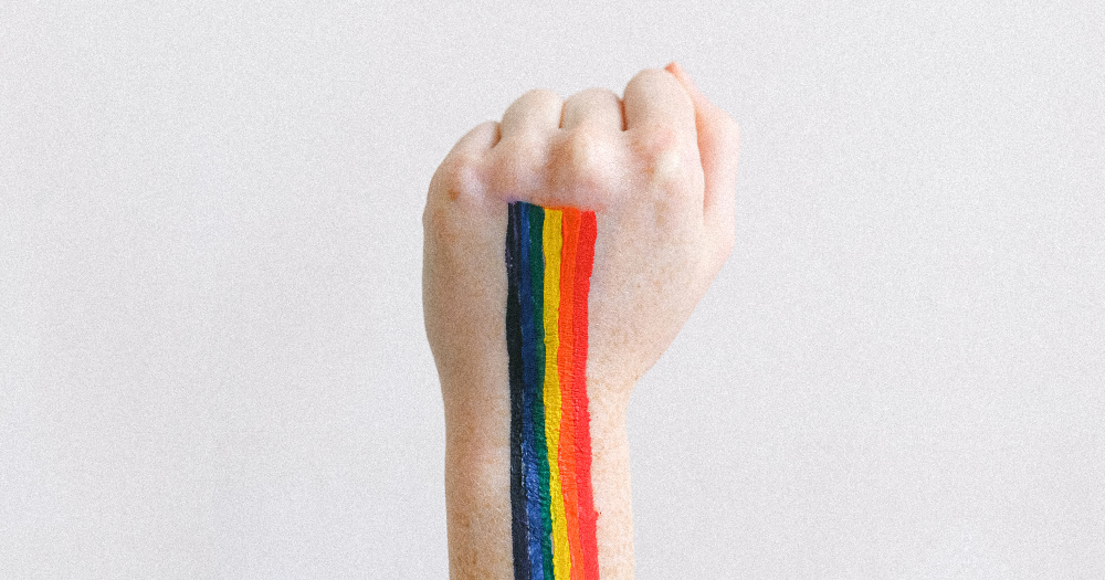 LGBTI+ Community Service a clenched fist against with a rainbow stripe against a white background