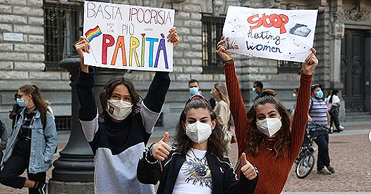 Three people with signs supporting hate crime legislation in Italy